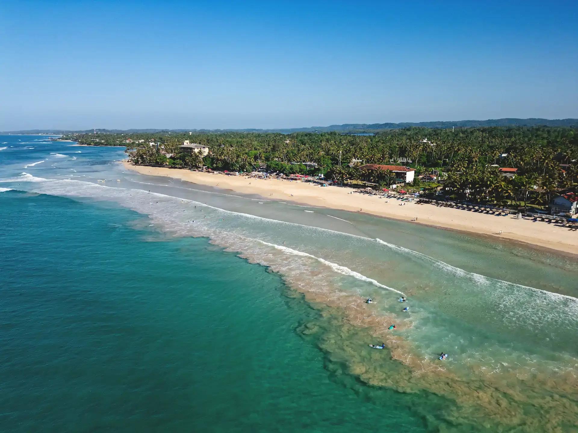 Turquoise waves roll into the palm-lined beach at Kabalana, Sri Lanka