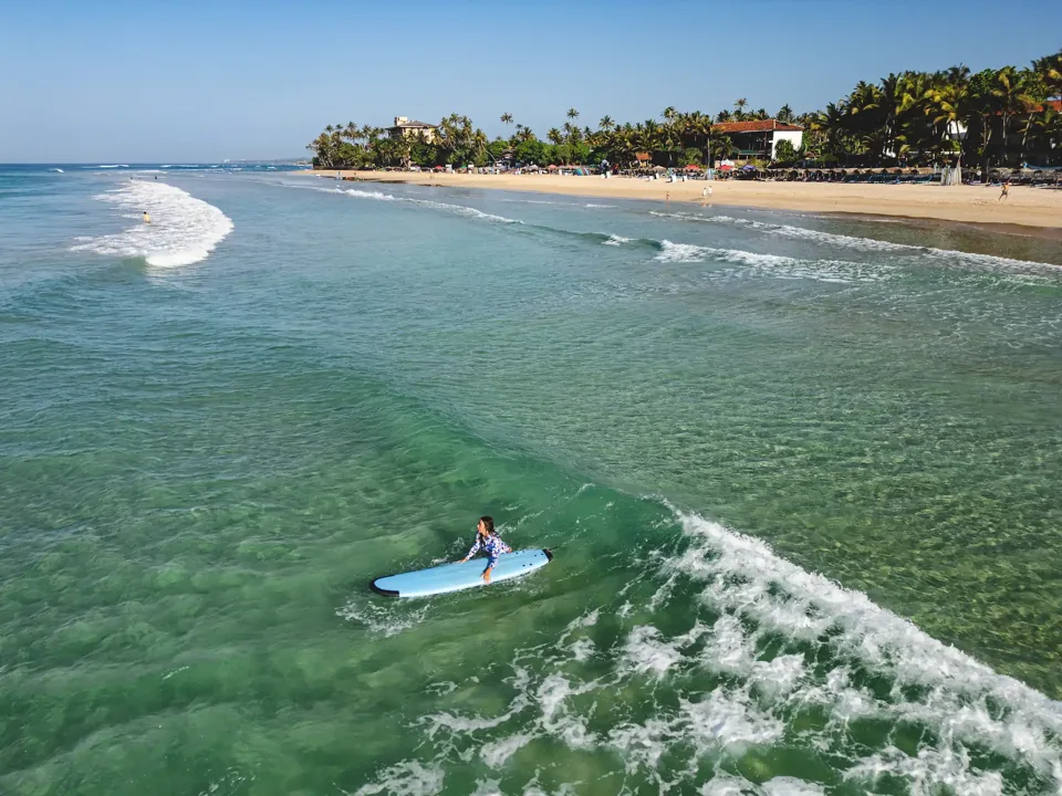 A surfer rides a small wave along Kabalana’s coastline