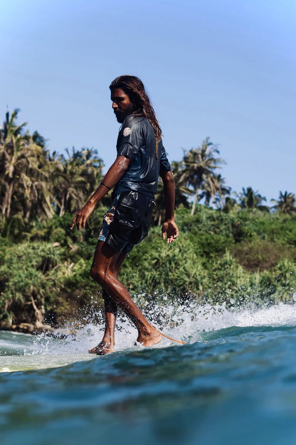 A surfer practises longboard footwork on a small wave in Ahangama