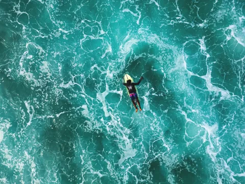 A surfer surrounded by turquoise waves